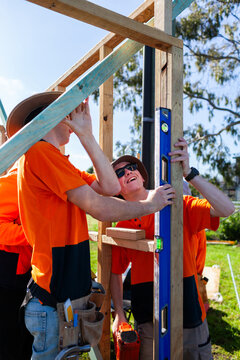 Apprentice trade workers building frame using level together to check the plumb