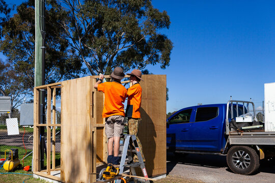 Two trade apprentice workers building ticket booth at local sports grounds - hands on learning