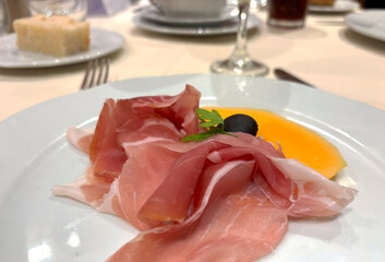 Slices of prosciutto on white plate