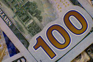 Detailed view of a one hundred dollar bill showcasing intricate designs and vibrant colors under...