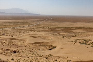 Vast desert landscape in balkh province afghanistan with a lonely road and mountains