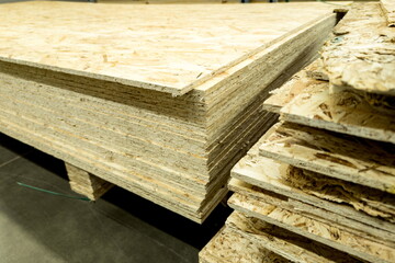 Plywood sheets stacked in a warehouse for construction projects during daylight hours