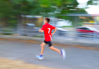  teenager boy running in green park. Blur.