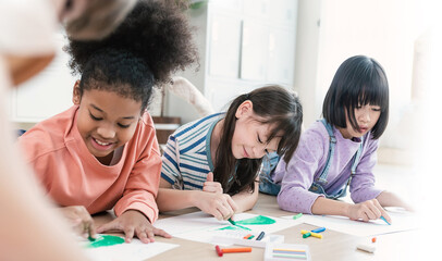 Group of multicultural kids happily drawing with crayons on the floor during an art activity in a bright classroom setting. Education back to school