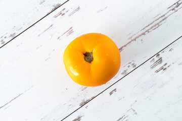 Yellow tomato, fresh from farmers market, on white-washed distressed wood surface
