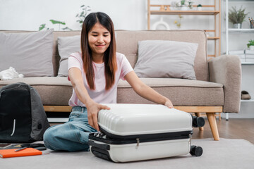 Smiling woman packing suitcase in a stylish living room, preparing for a travel adventure. Modern decor and cozy atmosphere.