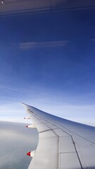 Singapore- 16 Aug 2025: vertical photo of aircraft plane wing in a blue sky with copy space taken from plane window with copy space © Tiffany