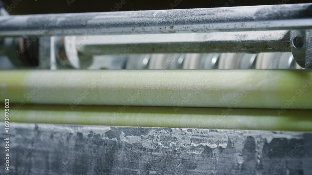 Poster close up view of several industrial rollers rotating synchronously in a factory setting, potentially