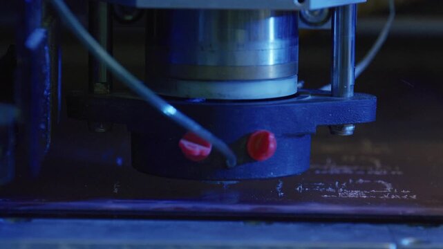 Close up view of automated industrial laser engraving machine precisely etching intricate design onto metal plate in modern factory setting