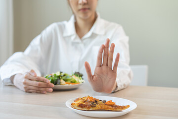 Diet concept, asian young woman close up hand push out away Pizza, refuse junk process, carb food on plate, choose green vegetable salad, eat low fat for good health. Female people getting weight loss