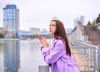 Fototapeta premium There is a woman in a purple coat standing on the pier, with a view of the pond. She has a beautiful and slender figure.
