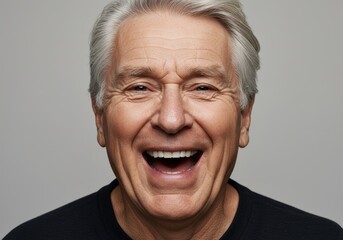Obraz premium Joyful senior man with gray hair laughing heartily.