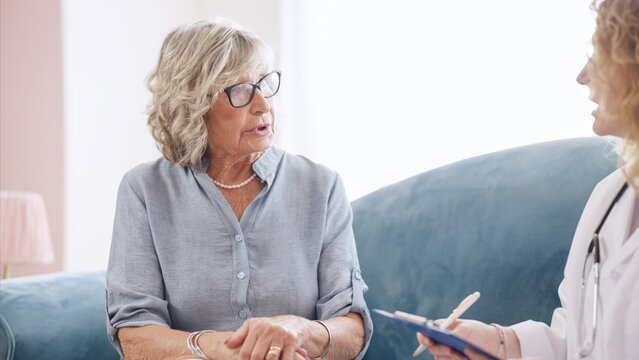 Senior woman describing symptoms to doctor during home visit - Powered by Adobe