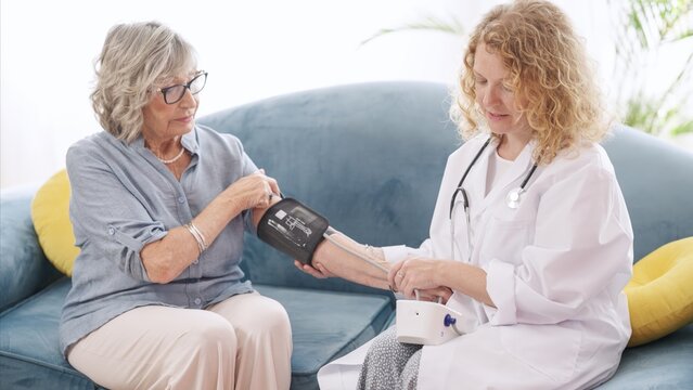 Healthcare professional checking blood pressure of senior woman