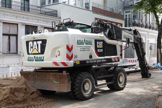 Ein weisser Mobilbagger Marke CAT M320F in einer Fussg&auml;ngerzone