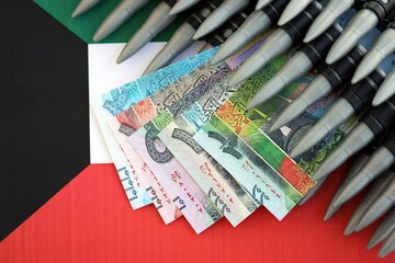 Kuwaiti dinar currency money bills and rifle bullets on flag. The concept of warfare and gun selling
