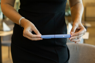 A woman in a black dress holding an ozempic pen, concept of medical treatment, modern healthcare, and weight loss solutions.