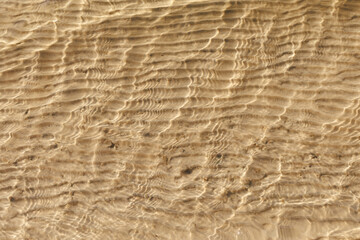 Under water texture light shadows on the beach sand. Close up