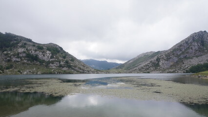 Naklejka premium Mountain lake surrounded by rocky hills and cloudy sky