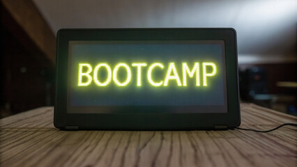 Bootcamp sign glowing brightly on digital display, showcasing word BOOTCAMP in vibrant yellow letters. setting is modern workspace, creating energetic atmosphere