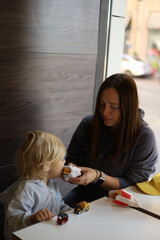 Woman feeding her three-year-old son a burger in a fast-food restaurant