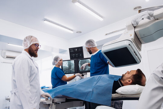 Medical professionals in surgical attire collaborating in a modern operating room, utilizing advanced angiograph technology for patient examination and diagnosis in a sterile environment