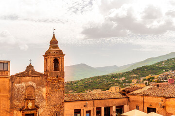 Fototapeta premium beautiful travel landscape of old european town with ancient church and vintage roofs in mediterranean style with amazing view to great green mountain and nice blue cloudy sky on background