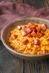 Rustic bowl of spicy tomato and chorizo risotto on wooden table
