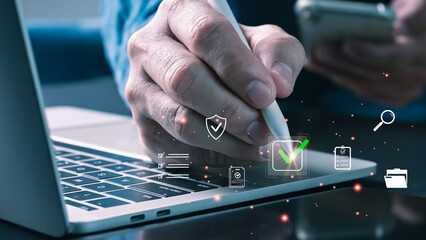 A professional uses a stylus on a laptop, interacting with a digital checkmark and quality icons,...