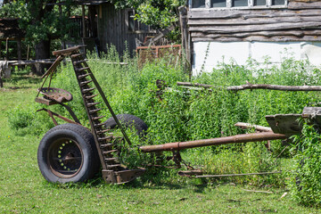 Agricultural equipment. Metal harrow, two wheels in the grass. Old abandoned farm