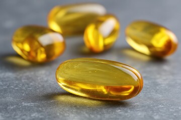 Close-up of several yellow gelatin capsules on a gray surface