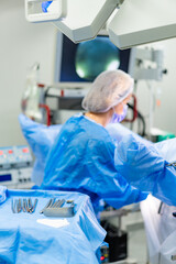 Surgeon operates in sterile room. A surgeon in blue scrubs conducts a complex surgical procedure in...