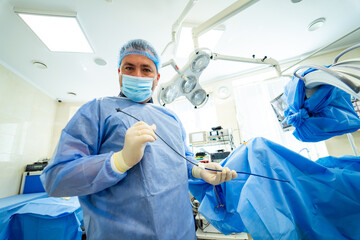 Surgical team prepares for an operation. Medical professional in surgical attire holds instruments...