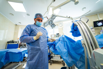 Surgeon operating in sterile room. Surgeon is focused on a procedure in a modern operating room,...