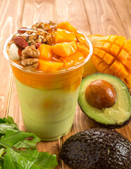 Avocado and Mango Smoothie with Nuts, Honey, and Fresh Fruit in glass side view of healthy drink