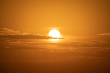 The bright sun shines through soft clouds in the warm sky, creating a beautiful light.