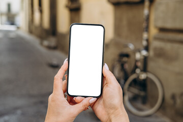 Smartphone mock up held by hands with blank screen in urban setting, showcasing modern technology...