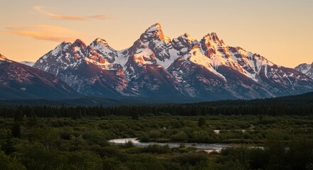 Obraz premium Snow covered mountain peaks over green landscape at sunset