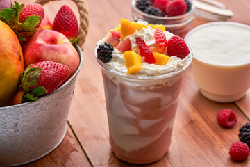 Creamy Fruit Smoothie or Parfait with strawberry, raspberry, mulberry, apple, and Mango, and Whipped Cream in plastic glass side view of Breakfast