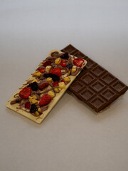 Two homemade chocolate bars—milk and white—packed with strawberries and nuts. A delicious blend of creamy chocolate and fresh fruit for a rich, natural treat.