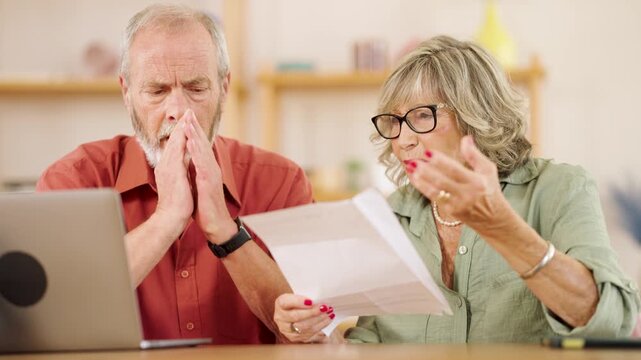 Senior couple worried reading bad news on documents at home