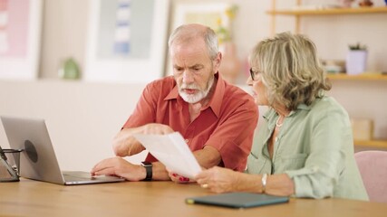 Senior couple examining documents and using laptop at home