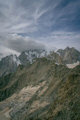 Alps mountain panorama with towering granite spires and snow patches beneath storm clouds creating dramatic high altitude scenery