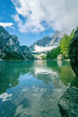 Iconic Lago di Braies Dolomites lake with emerald water and alpine mountains in background under sunny blue sky creating peaceful view