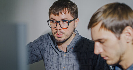 Team adult male engineer collaborate on robotic hand project using AI code solutions machine learning at tech workspace. Artificial intelligence interface, collaboration support prototype development.