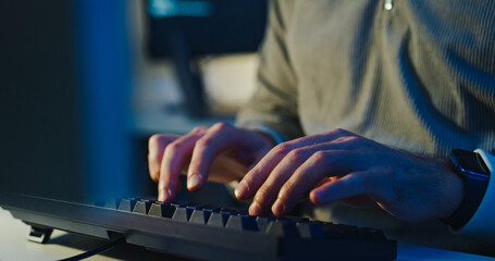 Closeup young adult male freelance developer typing write prompt AI bot app program nomad terminal coding at office night. Artificial intelligence dashboard, robotics user interface, machine learning.