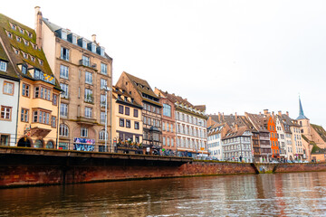 Enjoy a beautiful view of Colmar's historic buildings adorned for Christmas along the tranquil river. The festive spirit brings warmth to the city's picturesque scenery.