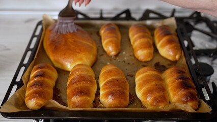 Baker glazing freshly baked bread with egg yolk