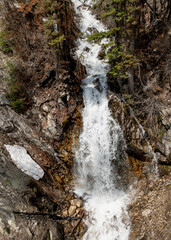 Mountain waterfall flows over a rock cliff