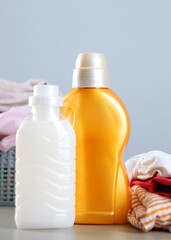 Laundry detergent bottles and clothes on the table. Household chemicals. Vertical photo format